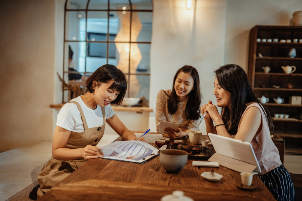 Featured image of three Asian women sitting around a table while looking at a tablet