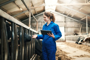 Feature image of a young white woman wearing a blue jumpsuit next to some cows