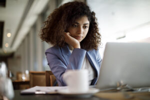 A Black woman sitting at a desk looking at a computer