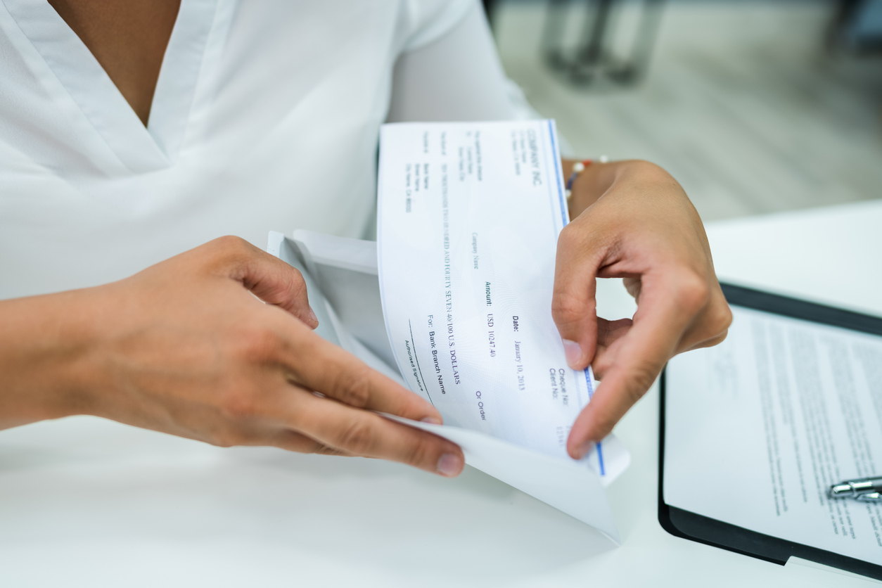 Close-up off a woman's hands holding a paycheck